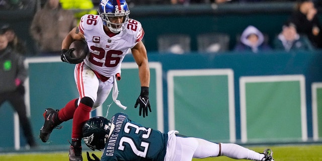 El corredor de los New York Giants, Saquon Barkley, n.º 26, corre con el balón mientras el profundo de los Philadelphia Eagles, CJ Gardner-Johnson, n.º 23, intenta detenerlo durante la segunda mitad de un partido de fútbol de playoffs de la Ronda Divisional de la NFL el sábado 21 de enero.  2023, en Filadelfia.