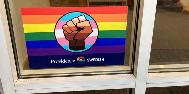 A rainbow sticker packed with combined symbolism is prominently displayed in the window of a primary care clinic in an upscale Seattle neighborhood. (Elizabeth Economou)