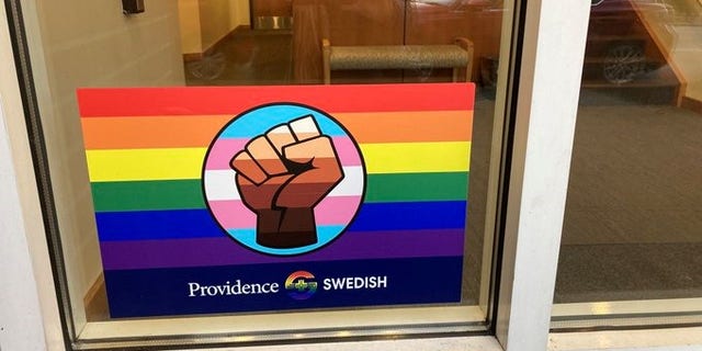 A rainbow sticker packed with combined symbolism is prominently displayed in the window of a primary care clinic in an upscale Seattle neighborhood. (Elizabeth Economou)