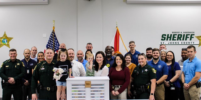 Kirsten Bridegan and her daughters Bexley and London pose with St. Johns County Sheriff Robert Hardwick and other law enforcement officers. 