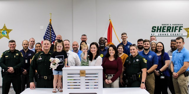 Kirsten Bridegan and her daughters Bexley and London pose with St. Johns County Sheriff Robert Hardwick and other law enforcement officers. 