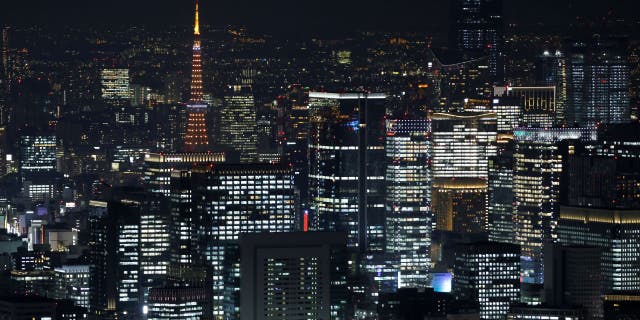 The illuminated Tokyo Tower, top left, among illuminated commercial and residential buildings at night in Tokyo.