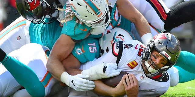 Tom Brady of the Buccaneers is fired by Jerome Baker of the Miami Dolphins at Raymond James Stadium on October 10, 2021 in Tampa, Florida.