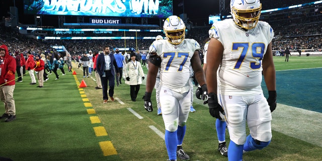 Los Angeles Chargers offensive tackle Trey Pipkins III (79) and Los Angeles Chargers guard Zion Johnson (77) walk off the field after losing to the Jaguars at TIAA Bank Field.