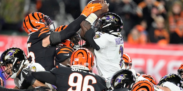 Quarterback Baltimore Ravens Tyler Huntley (2) meraba-raba bola saat dijatuhkan oleh gelandang Cincinnati Bengals Logan Wilson, kiri, di paruh kedua pertandingan sepak bola playoff kartu liar NFL di Cincinnati, Minggu, 15 Januari 2023. Sam Hubbard dari Bengals memulihkan kesalahan dan menjalankannya kembali untuk touchdown.