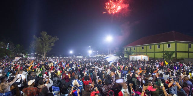 Fireworks light up the sky as people react while they celebrate after counting down to the new year in Kampala, Uganda, on Jan. 1, 2023. A stampede occurred just before the firework show leaving 10 dead.