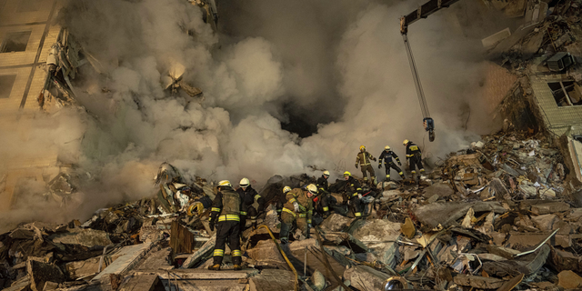 Emergency workers clear the rubble after a Russian rocket hit a multistory building, leaving many people under debris, in the southeastern city of Dnipro, Ukraine, on Saturday, Jan. 14.