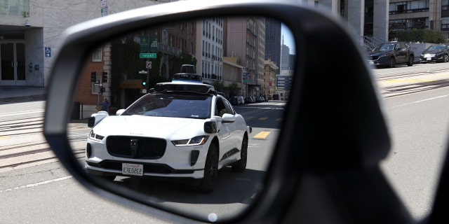 Kendaraan otonom Waymo terlihat terpantul di cermin saat melaju di sepanjang California Street pada 11 April 2022, di San Francisco, California.