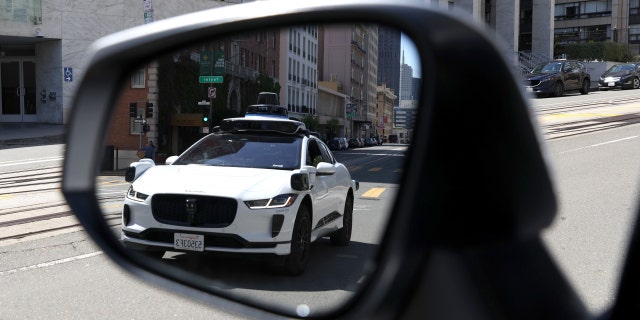 A Waymo autonomous vehicle is seen reflected in a mirror as it drives along California Street on April 11, 2022, in San Francisco, California. 