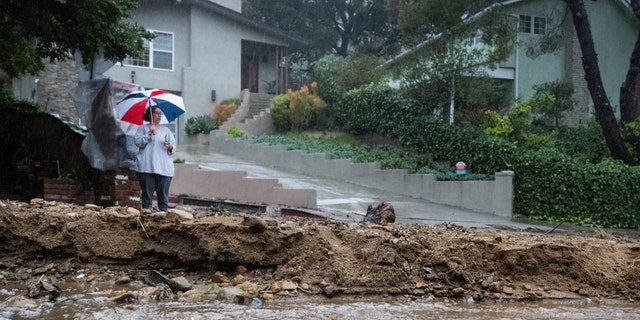 A resident keeps watch on Fredonia Drive in Studio City, where a mudslide is blocking the road during the storm on Tuesday, Jan. 10, 2023. 