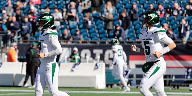 New York Jets quarterbacks Zach Wilson (2) en Mike White (5) rennen het veld op om op te warmen voor een wedstrijd tegen de New England Patriots op 24 oktober 2021 in het Gillette Stadium in Foxborough, Massachusetts. 