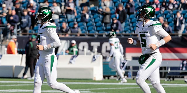 New York Jets quarterbacks Zach Wilson (2) and Mike White (5) run onto the field to warm up before a game against the New England Patriots Oct. 24, 2021, at Gillette Stadium in Foxborough, Mass.