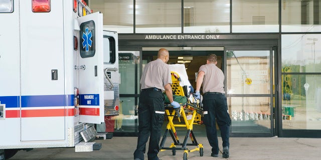 Paramedics taking patient on stretcher from ambulance to hospital