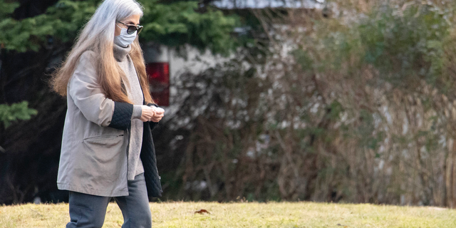 A woman who appears to be Diana Walshe walking in gray coat.