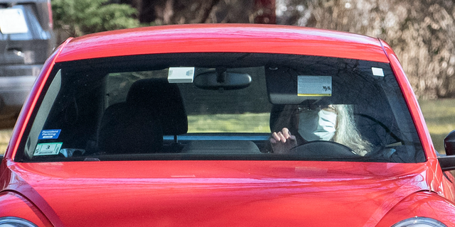 A woman who appears to be Diana Walshe driving a red VW Bug.