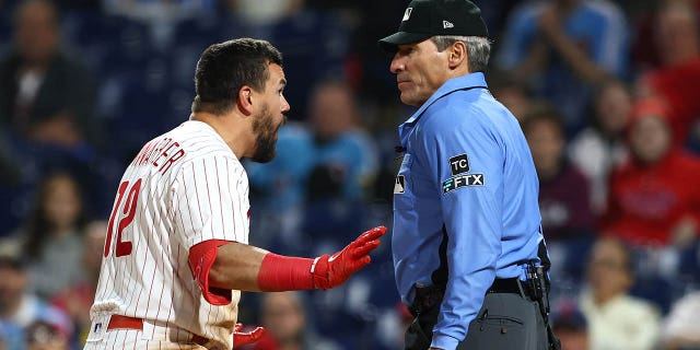 Kyle Schwarber #12 of the Philadelphia Phillies argues with plate umpire Angel Hernandez after being called for strikes during the ninth inning against the Milwaukee Brewers at Citizens Bank Park on April 24, 2022 in Philadelphia, Pennsylvania.  The Brewers defeated the Phillies 1-0.