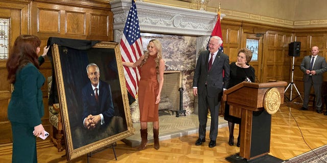 Arkansas Gov. Asa Hutchinson and first lady Susan Hutchinson look on as their granddaughter, Jaella Wengel, left, and daughter, Sarah Wengel, center, unveil the governor’s official portrait on Tuesday, Jan. 3, 2023, at the state Capitol in Little Rock, Ark. Hutchinson will leave office on Jan. 10 after serving eight years as governor. (AP Photo/Andrew DeMillo)