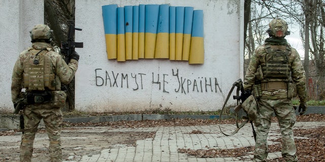 BAKHMUT, UKRAINE – JANUARY 4: Ukrainian soldiers stand near a stele with a Ukrainian flag and a handwritten inscription that reads: