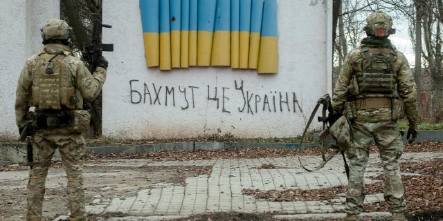 BAKHMUT, UKRAINE – JANUARY 4: Ukrainian soldiers stand near a stele with a Ukrainian flag and a handwritten inscription that reads: "Bakhmut is Ukraine" on January 4, 2023 in Bakhmut, Donetsk Oblast, Ukraine.