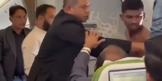 Passengers try to break up a fight on Biman Bangladesh flight.