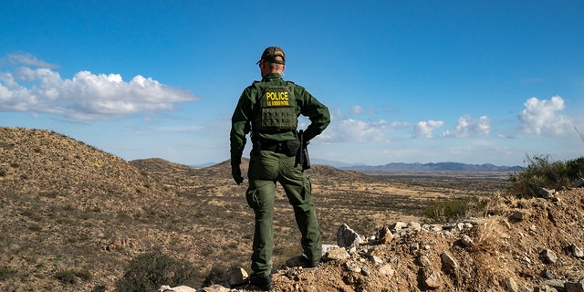 Un agente de la Patrulla Fronteriza de EE. UU. se encuentra en un acantilado en busca de migrantes que cruzaron el muro fronterizo entre EE. UU. y México cerca de la ciudad de Sasabe, Arizona, el 23 de enero de 2022.