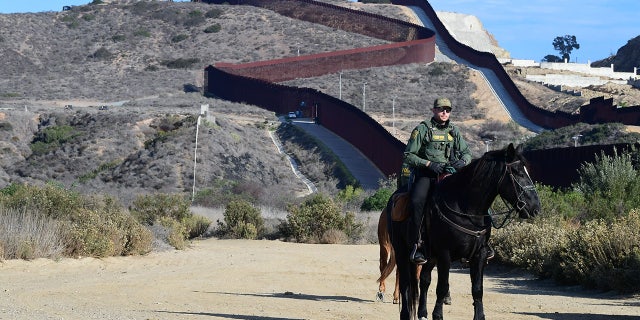 Un agent de la patrouille frontalière à cheval surveille la zone près de l'endroit où la barrière frontalière américano-mexicaine rencontre l'océan Pacifique le 7 novembre 2021.