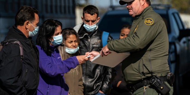 Migrants wait for their turn to have a Border Patrol agent write down their information in Eagle Pass, Texas on Dec. 20, 2022. 