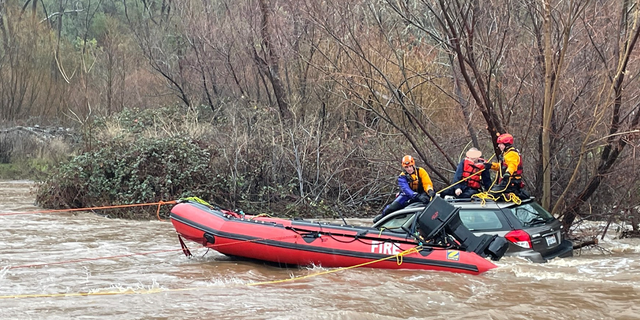 A rescue team with raft rescues man trapped in floodwaters in California.