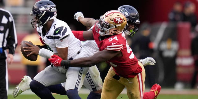 Seattle Seahawks quarterback Geno Smith (7) is pressured by San Francisco 49ers defensive end Charles Omenihu (94) during the second half of an NFL wild card playoff football game in Santa Clara, Calif., Saturday, Jan. 14, 2023.