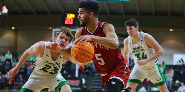 Denver's Coban Porter (5) drives to the basket while being guarded by North Dakota's Paul Bruns (23) and Brian Mathews, Feb. 3, 2022, at the Betty Engelstad Sioux Center in Grand Forks, North Dakota.