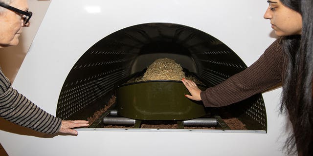 Two people look at a shrouded mannequin inside the Threshold Vessel in the Gathering Space at Recompose, a green funeral home specializing in human composting, also known as natural organic reduction, terramation, or recomposition at Recompose Seattle on October 06, 2022 in Seattle, Washington. 