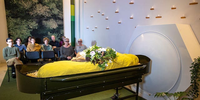 Guests sit in the gathering space looking at a shrouded mannequin in front of the threshold vessel at Recompose, a green funeral home specializing in human composting, also known as natural organic reduction, terramation, or recomposition at Recompose Seattle on October 06, 2022 in Seattle, Washington. 