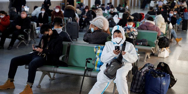 Seseorang yang mengenakan pakaian pelindung duduk di Stasiun Kereta Api Beijing menjelang Tahun Baru Imlek di Beijing, pada 20 Januari 2023.