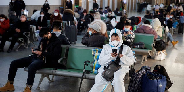 A person wearing a protective suit sits in Beijing Railway Station ahead of Chinese Lunar New Year in Beijing, on Jan. 20, 2023.