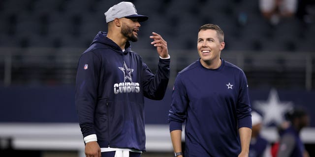 Quarterback Dak Prescott #4 of the Dallas Cowboys talks with offensive coordinator Kellen Moore of the Dallas Cowboys on the field during pregame warm-ups before the Dallas Cowboys take on the Houston Texans in a preseason NFL game at AT&amp;amp;T Stadium on August 21, 2021 in Arlington, Texas.