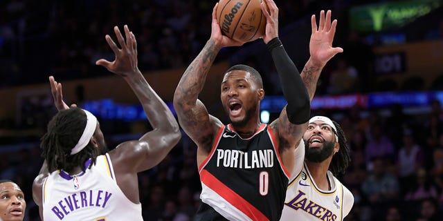 Damian Lillard #0 of the Portland Trail Blazers looks to pass the ball under pressure from Patrick Beverley #21 and Anthony Davis #3 of the Los Angeles Lakers during the first half of the game at Crypto.com Arena on October 23, 2022 in Los Angeles, California.