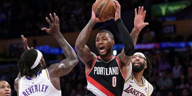 Damian Lillard #0 of the Portland Trail Blazers looks to pass the ball under pressure from Patrick Beverley #21 and Anthony Davis #3 of the Los Angeles Lakers during the first half of the game at Crypto.com Arena on October 23, 2022 in Los Angeles, California.