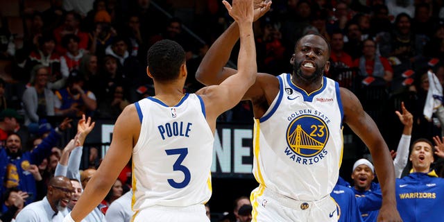 Jordan Poole #3 of the Golden State Warriors high fives with Draymond Green #23 during the game against the Toronto Raptors on December 18, 2022 at Scotiabank Arena in Toronto, Ontario, Canada.