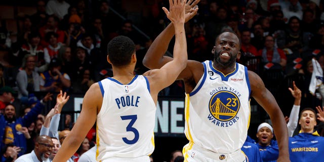 Jordan Poole #3 of the Golden State Warriors high-fives Draymond Green #23 during the game against the Toronto Raptors on December 18, 2022, at the Scotiabank Arena in Toronto, Ontario, Canada.