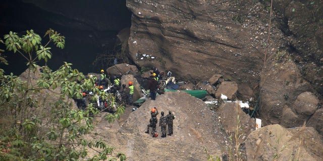 Nepalese rescue workers inspect wreckage at the site of a plane crash in Pokhara, Nepal, Monday, Jan. 16, 2023.
