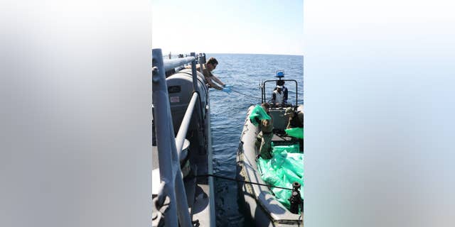 U.S. Navy servicemen transfer 2,000 assault rifles confiscated from an Iranian smuggling vessel.