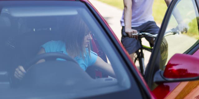 Woman improperly opens a car door and puts a cyclist in great danger on the road.