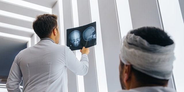 A health care professional examines an X-ray of a patient's head; the man had suffered a head injury.