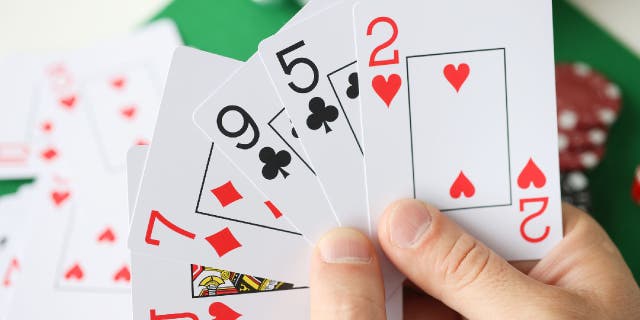 Man holds poker playing cards. The state of North Dakota has specific laws about limits on poker playing at events. 