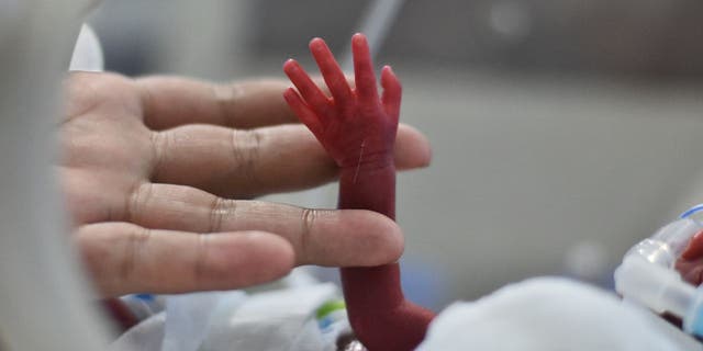 Baby in NICU raising small hand