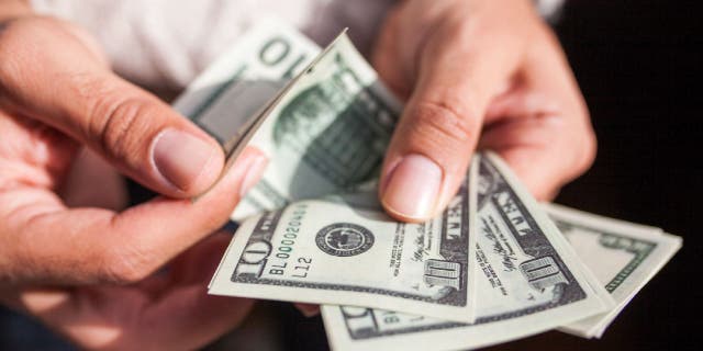 U.S. dollar currency is held by a person.