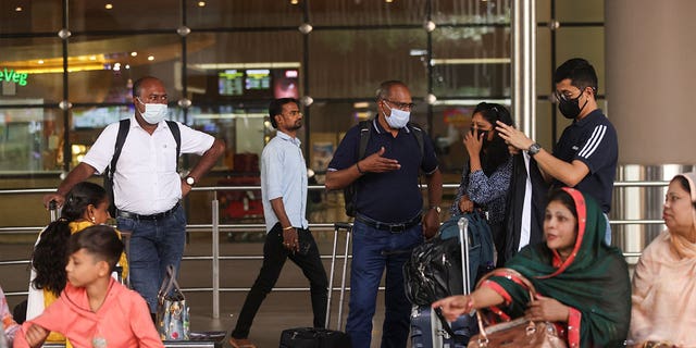 People wait for their luggage while wearing masks at the Chhatrapati Shivaji Maharaj International Airport in Mumbai, India, on Dec. 22, 2022.
