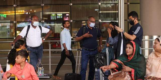 People wait for their luggage while wearing masks at the Chhatrapati Shivaji Maharaj International Airport in Mumbai, India, on Dec. 22, 2022.