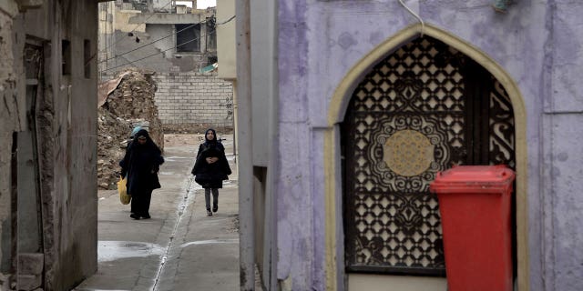 A building under construction collapsed Thursday in Iraq's northern city of Mosul, killing three and injuring nine. Pictured are Iraqi women walking in a partially renovated area in Mosul's war-damaged Old City, on Nov. 30, 2022.