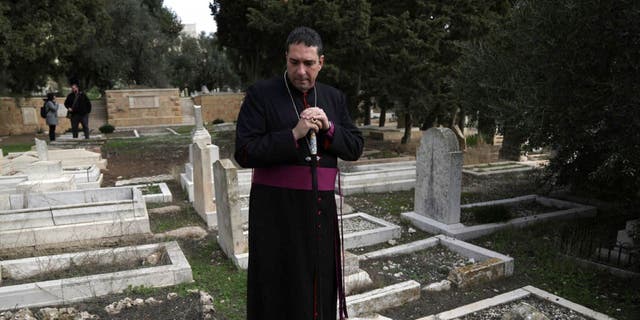 Hosam Naoum, a Palestinian Anglican bishop, pauses where vandals desecrated more than 30 graves at a historic Protestant Cemetery on Jerusalem's Mount Zion in Jerusalem, Wednesday, Jan. 4, 2023. Israel's foreign ministry called the attack an "immoral act" and "an affront to religion." Police officers were sent to investigate the profanation.  